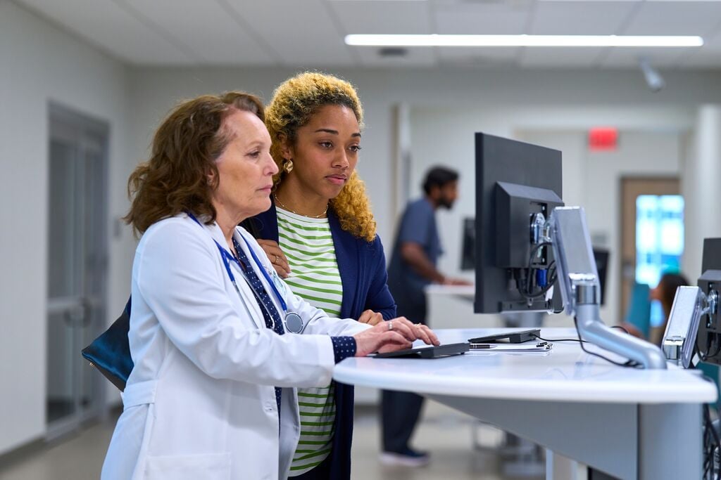 Patient and doctor looking at computer monitor in a hospital setting_