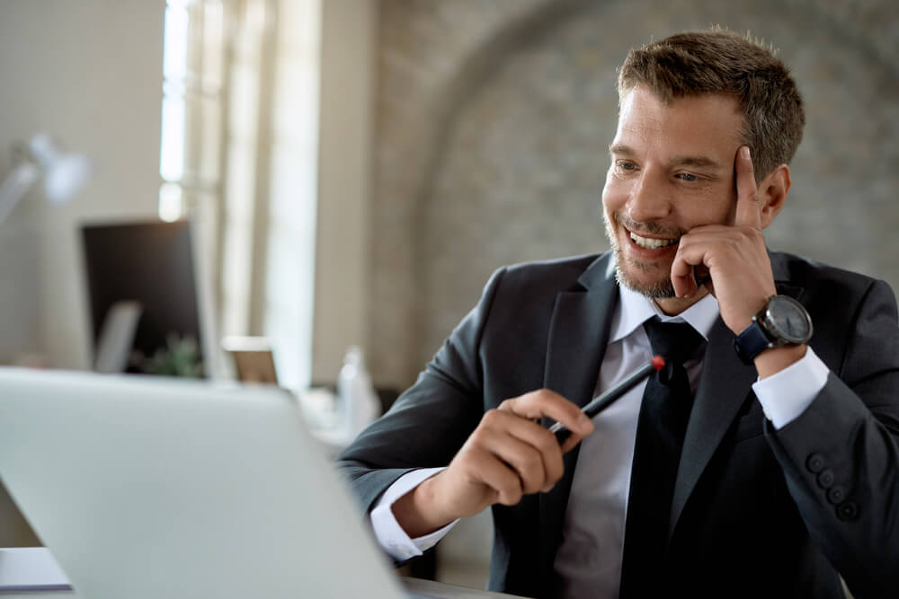 Professional man in business suite looking at laptop and smiling