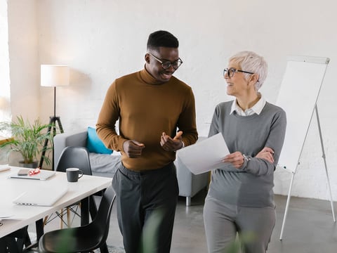 Two colleagues walking through office looking at paperwork
