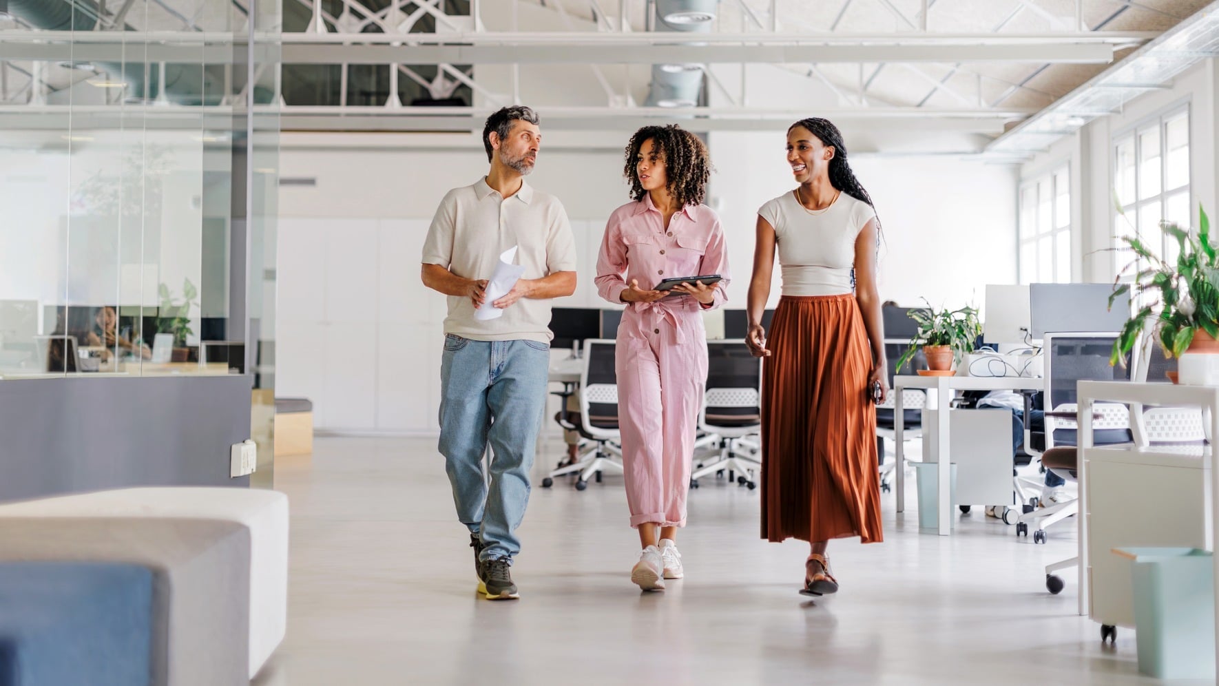 Three business people walking in an open office